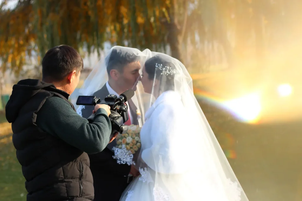 Videographer filming a bride and groom at golden hour